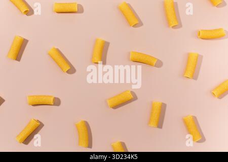 Ungekochte Rigatoni-Nudeln, verstreut auf rosafarbenem Hintergrund Stockfoto