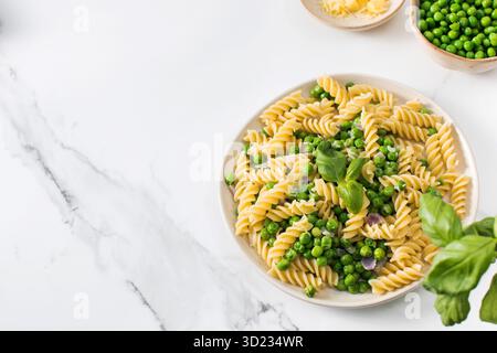 Vegetarische Pasta mit gekochten grünen Erbsen und Basilikum auf Teller Stockfoto