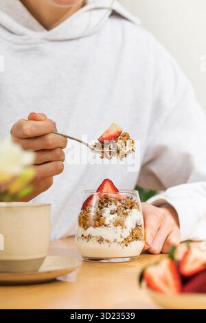 Frau isst Joghurt Parfait mit Müsli und Erdbeere Stockfoto