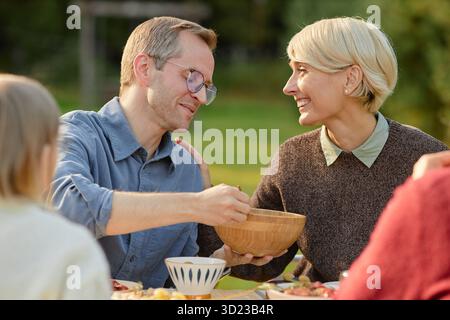 Kaukasischer Mann mittleren Alters, der draußen Essen mit kaukasischer Frau mittleren Alters teilt Stockfoto