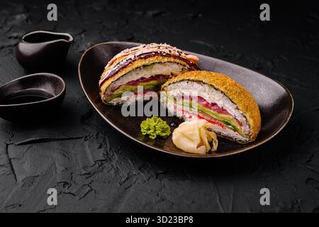 Köstlich zubereitetes Sushi-Sandwich mit Dippsoße auf schwarzem Teller Stockfoto