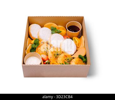 Eine köstliche Frühstückspaket mit flauschigen Hüttenkäsepfannkuchen mit Puderzucker, goldenen Käsefrittern und einer Mini-Pfanne Stockfoto