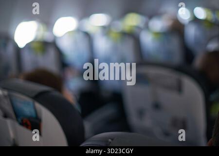 Verschwommene Flugzeugkabine mit Passagieren und Sitzreihe im Flug Stockfoto