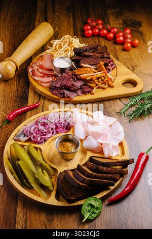 Wurstplatte mit verschiedenen Fleisch- und Gemüsesorten auf Holztisch Stockfoto
