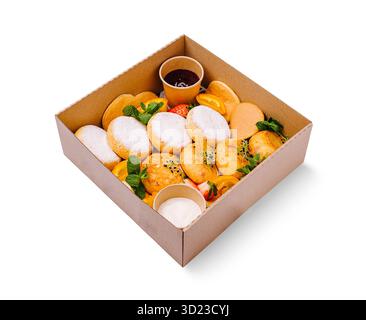 Eine köstliche Frühstücksbox mit flauschigen Hüttenkäse-Pfannkuchen, die mit Puderzucker bestäubt sind Stockfoto