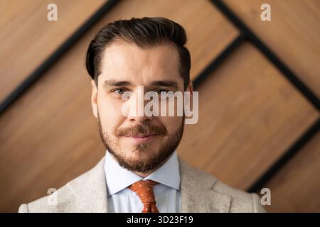 Lächelnder junger Geschäftsmann in klassischer schwarzer Hemdkrawatte, der isoliert im Büro posiert Stockfoto