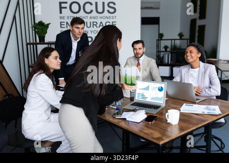 Kompetente IT-Spezialisten für stilvolle Outfits arbeiten an modernen Geräten, während sie zusammen in einem hellen Büro sitzen Stockfoto