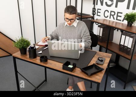 Geschäftsfrau, die im Büro mit Brille an einem Laptop arbeitet Stockfoto
