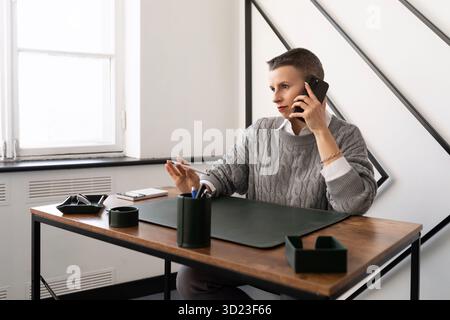 Reife Geschäftsfrau, die am Arbeitsplatz im Büro am Telefon spricht Stockfoto