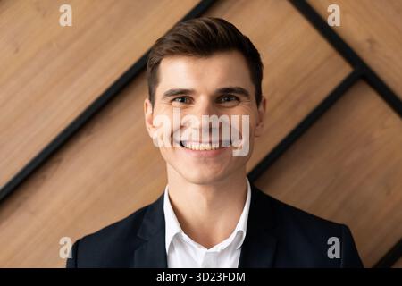 Porträt eines erfolgreichen jungen Geschäftsmannes mit einem Lächeln im Gesicht an der Wand im Büro Stockfoto