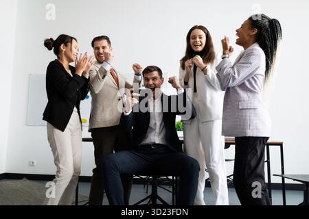 Jubelndes Business-Team, das auf den Smartphone-Bildschirm blickt Stockfoto