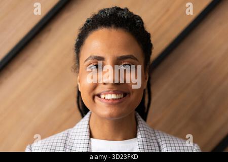 Porträt einer afroamerikanerin an einer Wand in einem Büro mit einem großen Lächeln im Gesicht Stockfoto