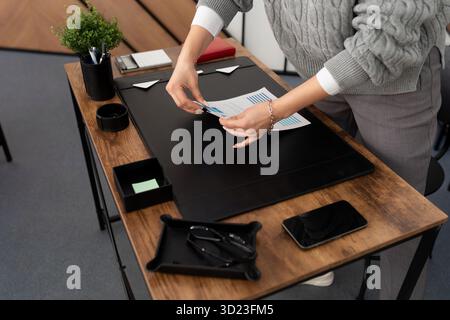 Geschäftsfrau an ihrem Schreibtisch im Büro faltet einen Stapel Dokumente Stockfoto