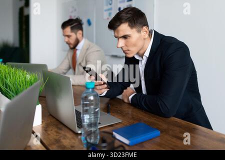 Büromitarbeiter in einem Meeting mit einem Mobiltelefon am Tisch Stockfoto