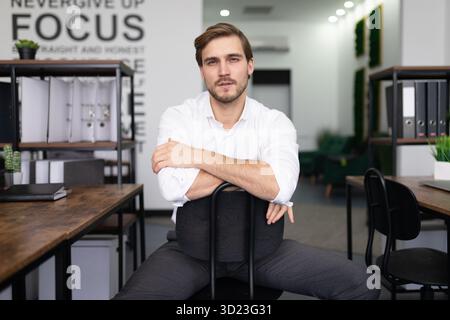 Ein junger Mann in Geschäftskleidung für ein Interview sitzt auf einem Stuhl Stockfoto