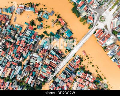 Aus der Vogelperspektive auf eine überflutete Stadt mit untergetauchten Straßen und bunten Dächern rund um eine Brücke. Cao Bang City, Cao Bang, Vietnam Stockfoto