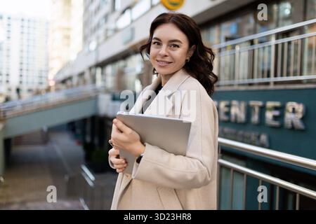 Geschäftsfrau mit einem Laptop in der Hand auf dem Hintergrund der Stadt Stockfoto