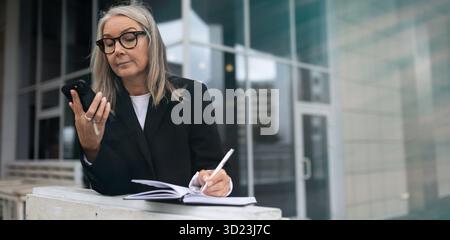 Ein älterer Geschäftsmann arbeitet außerhalb des Büros Stockfoto