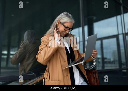 Kaukasische ältere Geschäftsfrau mittleren Alters in Brille, die draußen an einem Laptop arbeitet Stockfoto