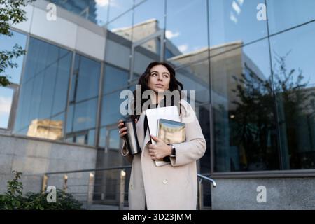 Porträt eines erfolgreichen jungen modernen Geschäftsmannes mit einem Laptop in der Hand auf dem Hintergrund eines Bürogebäudes, stark und Stockfoto
