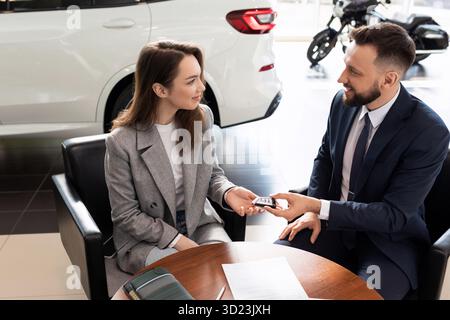 Der Manager des Autohändlers übergibt dem Neuwagenkäufer Schlüssel. Das Konzept des Mietwagens Stockfoto