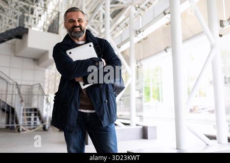 Porträt eines Geschäftsmannes in eleganter Freizeitkleidung mit Laptop vor einer Geschäftsreise am Flughafen im Wartezimmer Stockfoto