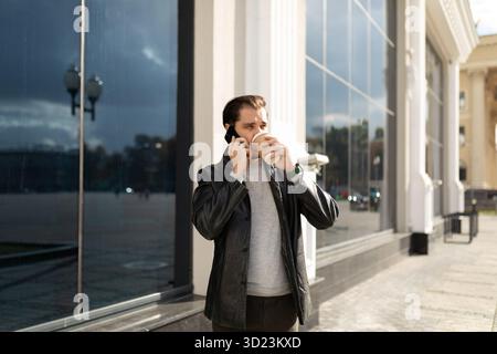 35-jähriger Mann, der in der Stadt Kaffee trinkt und telefoniert Stockfoto