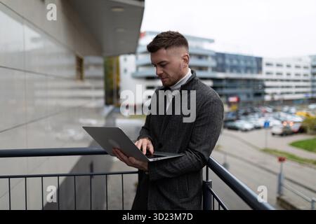 Erfolgreicher Geschäftsmann, der außerhalb des Büros an einem Laptop arbeitet Stockfoto