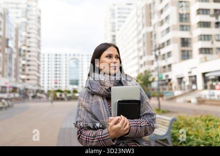 Porträt einer Geschäftsfrau mit Laptop in der Hand vor dem Hintergrund eines Wohnviertels, Geschäftsstrategie-Konzept Stockfoto