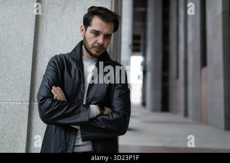 Ein herabhängender Mann in einem depressiven Zustand mit überkreuzten Armen auf der Brust steht und schaut nach unten Stockfoto