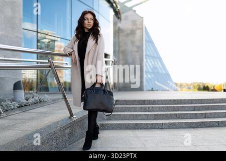 Stilvolle Geschäftsfrau mit einer Aktentasche in den Händen auf dem Hintergrund des Bürozentrums Stockfoto