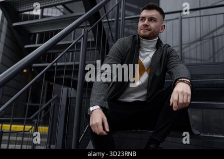 Porträt eines brutalen jungen Mannes, der auf der Treppe sitzt Stockfoto