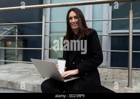Porträt einer erfolgreichen Geschäftsfrau mit Laptop vor dem Hintergrund eines modernen Bürogebäudes Stockfoto
