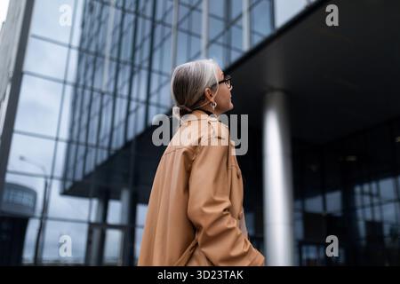 Eine grauhaarige Frau steht auf dem Kopf und inspiziert das Gebäude eines Geschäftszentrums Stockfoto