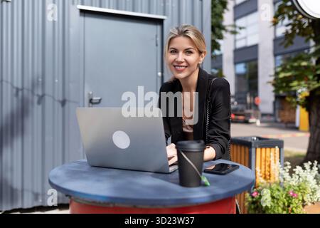 Porträt einer erfolgreichen jungen Frau, die im Café mit Laptop arbeitet Stockfoto