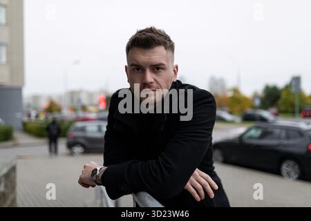 Porträt eines stilvollen Geschäftsmannes, der die Kamera vor dem Hintergrund der städtischen Landschaft betrachtet Stockfoto