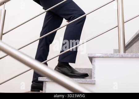 Nahaufnahme der Beine eines Geschäftsmannes, der die Treppe klettert, das Konzept eines erfolgreichen Geschäfts und Karrierewachstums Stockfoto