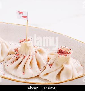 Knödel oder hinkali, serviert in einer Schüssel mit Zierflaggen und Gewürzen auf einem Tisch Stockfoto