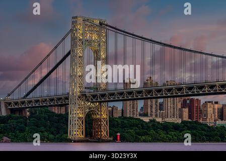 Beleuchtete Hängebrücke über den Fluss mit urbaner Skyline bei Sonnenuntergang. New York City, NY, USA George Washington Bridge, Hudson River Stockfoto