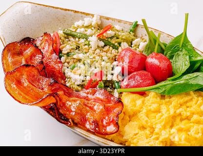 Köstliche Frühstücksschale mit Rührei, Gemüse und knusprigem Speck Stockfoto