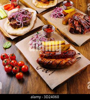 Köstliches gegrilltes Fleisch und frische Zutaten serviert auf einem Holztisch Stockfoto