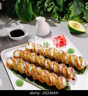 Sushi-Brötchen, wunderschön auf einer Platte mit frischen Zutaten angeordnet Stockfoto