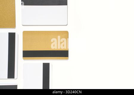 Goldene und weiße Kreditkarten mit schwarzen Streifen gegen weiß Stockfoto