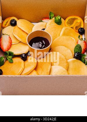 Köstliches Pfannkuchensortiment mit frischem Obst und Sirup, serviert in einer Box Stockfoto