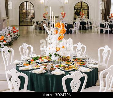 Ein wunderschön gestalteter Banketttisch bietet eine Vielzahl von Gourmet-Gerichten, umgeben von farbenfrohen Blumendekorationen. Der Veranstaltungsort ist raffiniert, mit Stockfoto