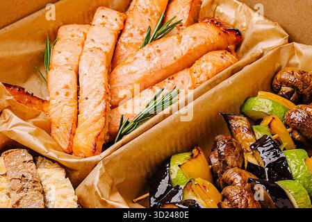 Gegrillter Lachs mit Gemüse, serviert in einem Karton bei einem Picknick Stockfoto