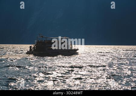 Passagierfähre auf der glitzernden Oberfläche des Gardasees in der Nähe von Limone sul Garda, Italien. Sommerreiseziel und Entspannungskonzept. Stockfoto