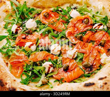 Köstliche Pizza mit Räucherlachs und frischem Gemüse in einem Restaurant Stockfoto
