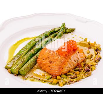 Lachsfilet mit Spargel und Pistazien, serviert auf einem weißen Teller Stockfoto