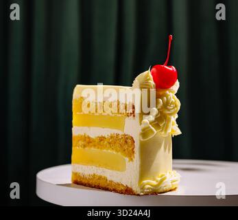 Köstlicher mehrschichtiger Kuchen mit Kirschgarnitur auf einem weißen Tisch in gemütlicher Atmosphäre Stockfoto